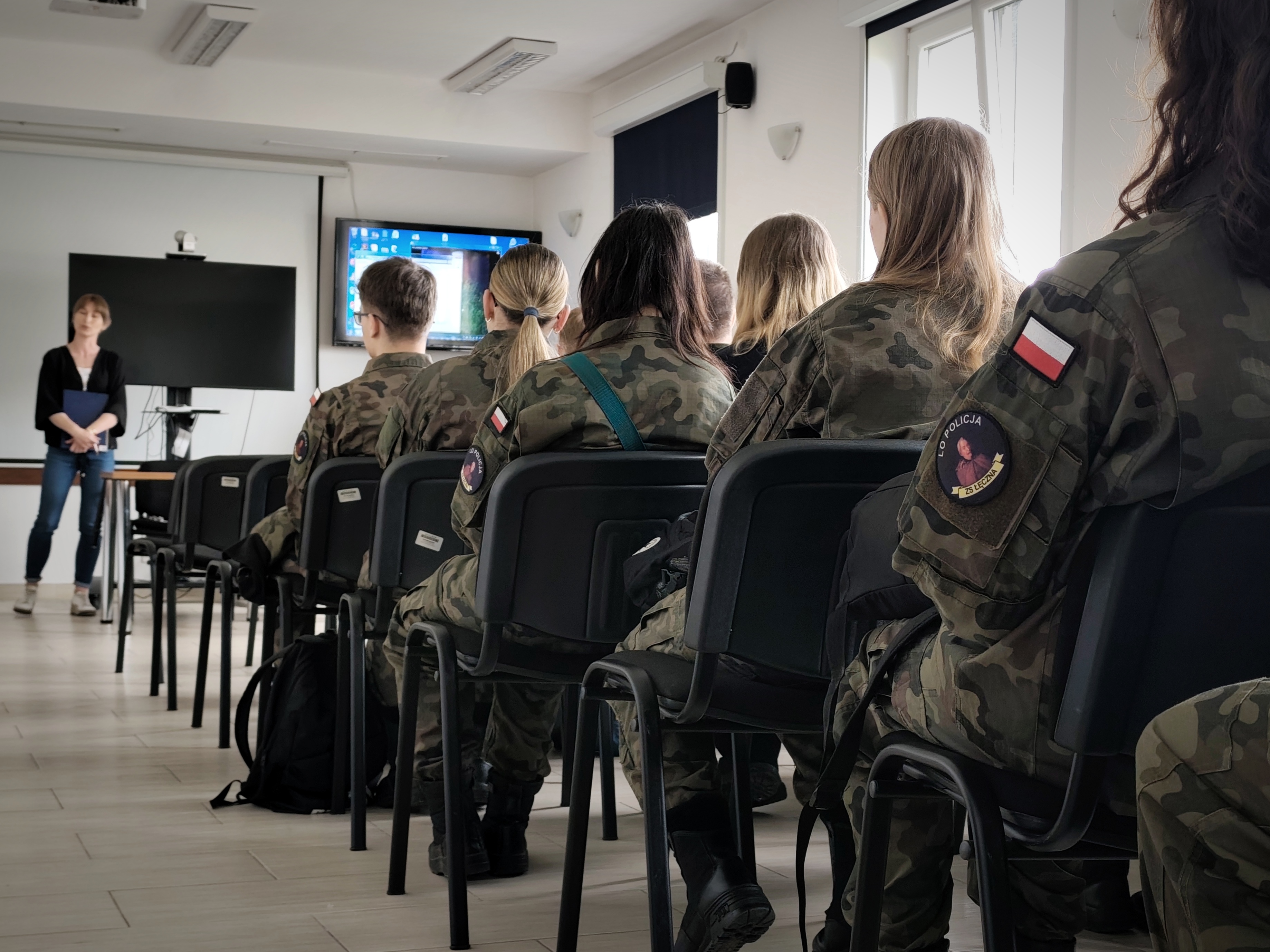 Uczniowie słuchający wykładu na temat pracy w policji i wymogów związanych z rekrutacją do policji 