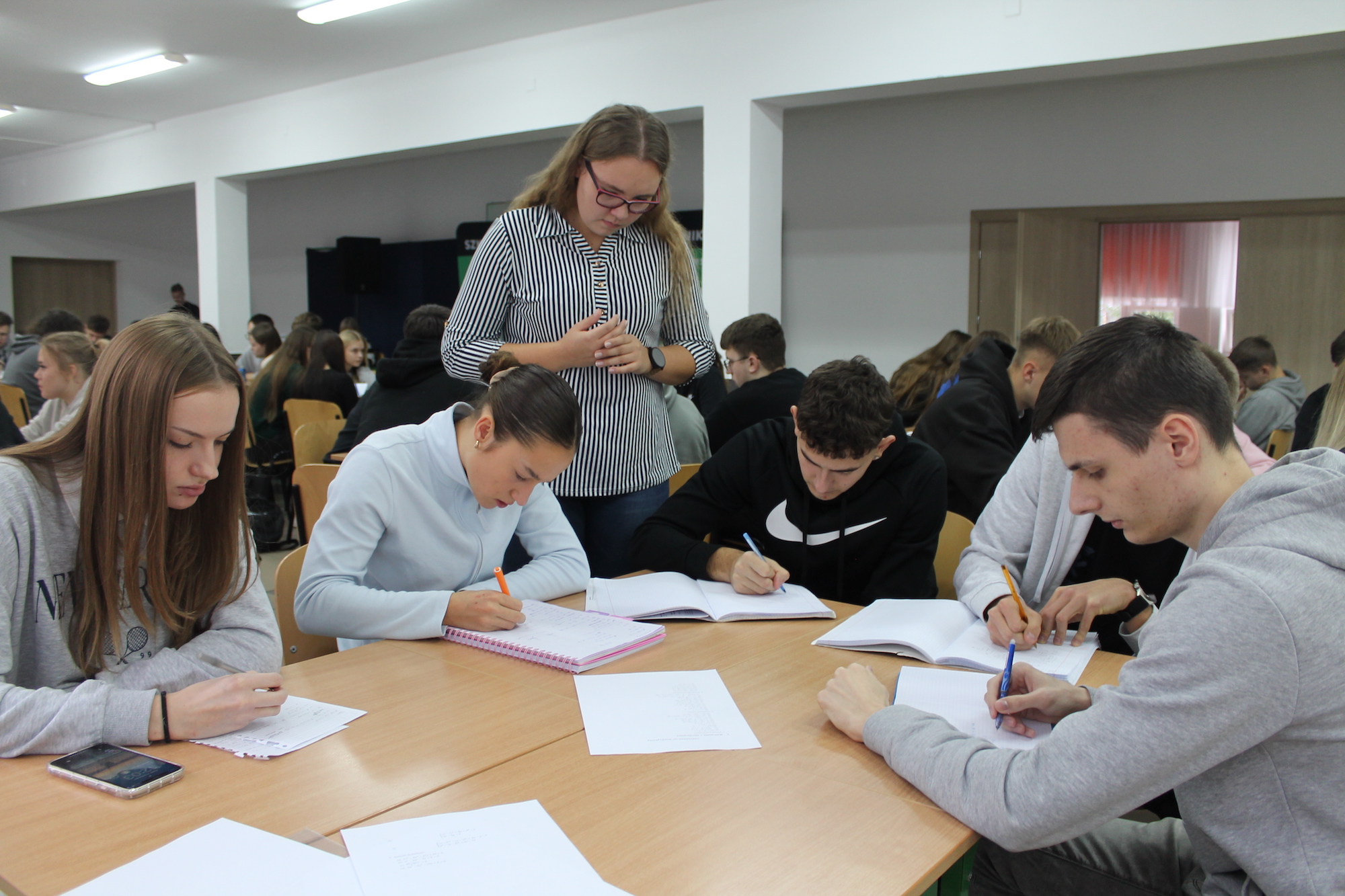 Uczniowie wykonujący zadania matematyczne pod okiem studentów 